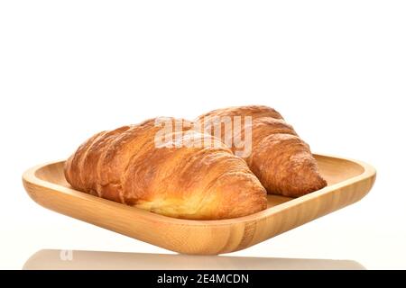 Deux croissants croquants frais et parfumés entiers avec plaque de bambou, gros plan, isolés sur du blanc. Banque D'Images