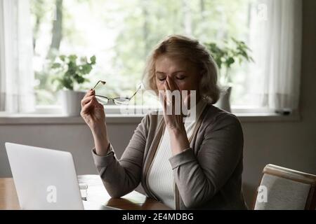 Femme mature épuisée prenant des lunettes, massant pont de nez Banque D'Images