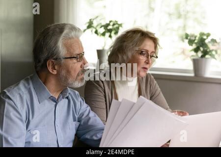 Gros plan sérieux couple mature vérification accord de prêt, lecture de documents Banque D'Images