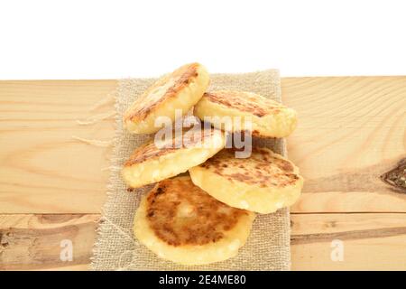 Quelques pancakes au fromage aromatisés et appétissants se trouvent sur une serviette en tissu qui repose sur un plan d'examen en bois. L'arrière-plan est blanc. Banque D'Images