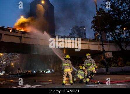 Les pompiers essaient d'éteindre un incendie d'une voiture en feu sur une autoroute en hauteur à Yau Ma Tei, Hong Kong. Banque D'Images