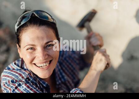 Femme de construction gaie avec un large grin tenant un marteau Banque D'Images