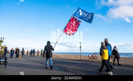 Worthing UK 24 janvier 2021 - UN homme avec une grande bannière remerciant le NHS pour leur travail pendant le coronavirus COVID-19 pandémie marche le long du front de mer de Worthing sur une belle journée ensoleillée : Credit Simon Dack / Alay Live News Banque D'Images