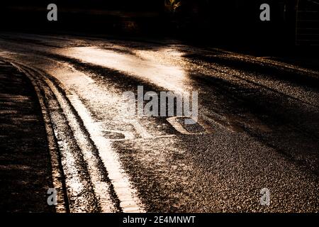 Signe lent peint sur une route à Bugbrooke, Northamptonshire en basse lumière du soleil d'hiver Banque D'Images