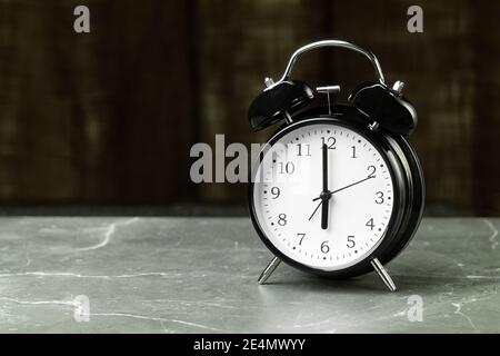 Les mains noires du réveil pointent vers six heures. Horloge et réveil sur la table avec espace pour le texte Banque D'Images