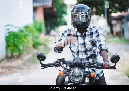 Motard africain dans le casque et les lunettes conduisant une moto manèges Banque D'Images