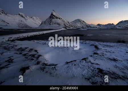 Textures de glace congelées intéressantes au premier plan de l'emblématique montagne Volandstind près de Fredvang sur Lofoten, Norvège. Banque D'Images