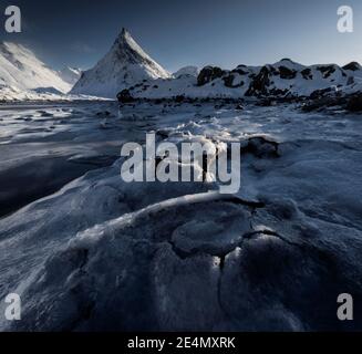 Textures de glace congelées intéressantes au premier plan de l'emblématique montagne Volandstind près de Fredvang sur Lofoten, Norvège, pendant un hiver froid ensoleillé jour. Banque D'Images