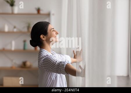 Bonne femme hindouiste ouvre des rideaux de fenêtre fermer les yeux dans le plaisir Banque D'Images