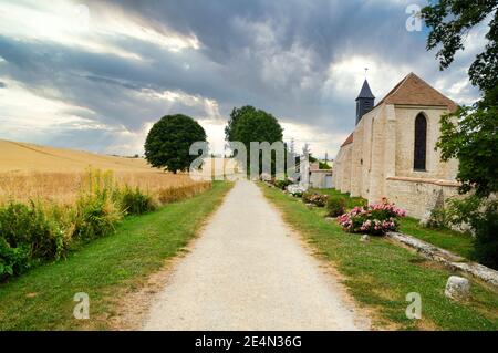 Magnifique paysage de campagne, avec un champ de blé et une église, sous un ciel orageux. Banque D'Images