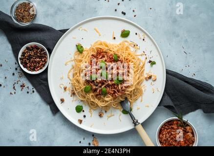 Pâtes bolognaises, fromage, parmesan et basilic sur fond gris. Banque D'Images
