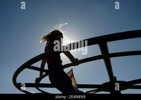 Silhouette d'une jeune fille sur un rond-point de terrain de jeu ou manège. Banque D'Images