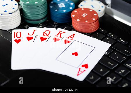 Plate-forme de jeu en ligne, casino et affaires de jeu. Cartes, dés et pièces de jeu multicolores sur le clavier de l'ordinateur portable. Banque D'Images