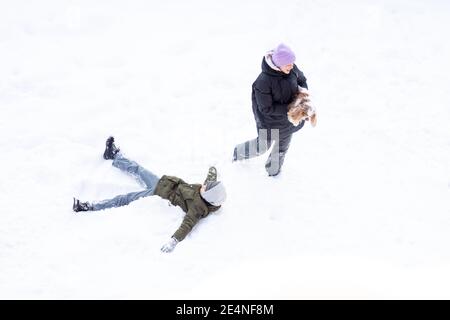 fille et garçon ont l'amusement à l'extérieur, la journée est neige, soeur et frère riant chien jouer la neige en hiver vêtements chauds. Vue de dessus Banque D'Images