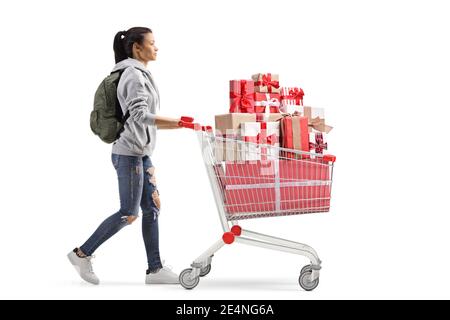 Prise de vue en profil d'une étudiante marchant et pousser un panier avec des cadeaux isolés sur fond blanc Banque D'Images