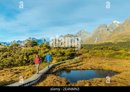 Randonnée en Nouvelle-Zélande. Jeune couple de randonnée pédestre sur le sentier de Routeburn Track pendant la journée ensoleillée. Les randonneurs portent des sacs à dos tout en faisant le pas sur Key Summit Banque D'Images