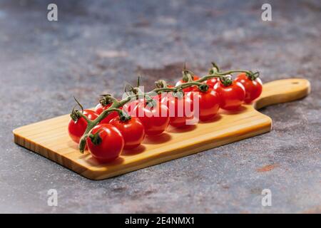 Les tomates britanniques Piccolo qui se trouvent sur la planche à découper sont de grande saveur, de belle couleur et de petite taille Banque D'Images