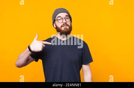 Photo de l'homme barbu pointant vers lui sur fond jaune. Banque D'Images