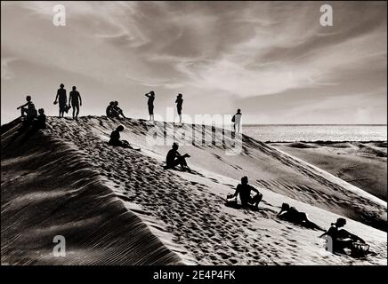 Les DUNES de Gran Canaria MASPALOMAS SONT DES VACANCES RÉTRO, intemporelles, tempérées, images de paysage d'art noir et blanc représentant un agencement surréaliste de personnes sur la crête d'une dune de sable, dans les dunes de Maspalomas, au sud de la Grande Canarie, aux îles Canaries, en Espagne. Banque D'Images