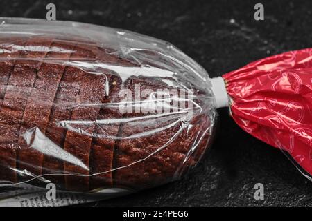 Tranches de pain noir de seigle dans un sac en plastique sur fond sombre Banque D'Images