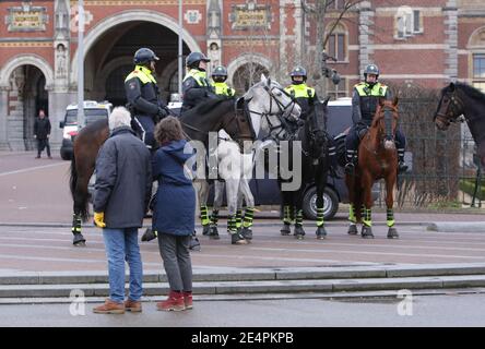Deux manifestants anti-verrouillage regardent la patrouille de police hollandaise anti-émeute montée Manifestation illégale au Museumplein dans le contexte de la pandémie du coronavirus Banque D'Images