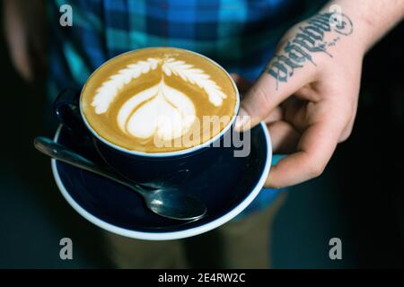 GRANDE-BRETAGNE / Angleterre / Londres/main avec tatoo tenant le café Tasse dans un café intérieur à Londres.gros plan des mains contenant une tasse de café Banque D'Images