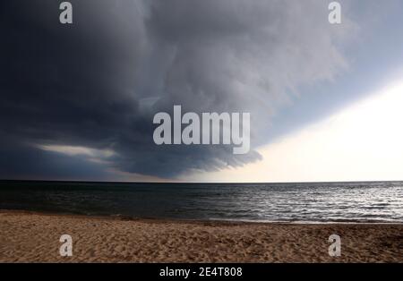 Un front de tempête inquiétant qui descend sur une plage urbaine. Banque D'Images