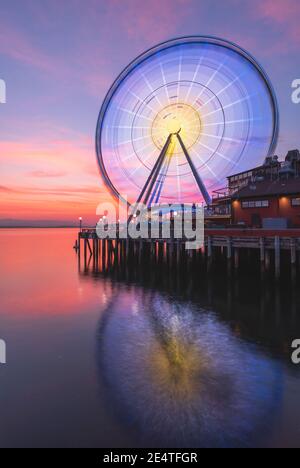 La grande roue de Seattle s'élève à 175 mètres au-dessus de l'embarcadère 57, surplombant les gratte-ciel de Seattle et Elliott Bay tandis que le soleil se couche à l'ouest Banque D'Images