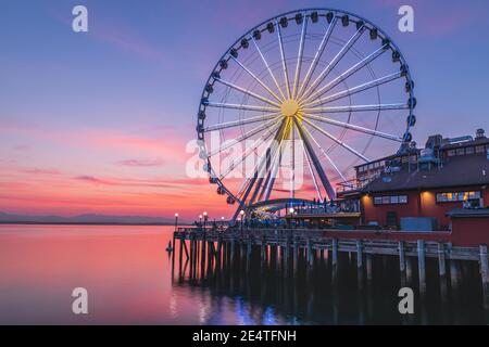 La grande roue de Seattle s'élève à 175 mètres au-dessus de l'embarcadère 57, surplombant les gratte-ciel de Seattle et Elliott Bay tandis que le soleil se couche à l'ouest Banque D'Images