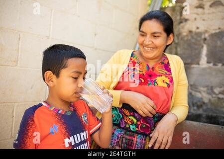 Un enfant boit un verre d'eau propre à San Juan la Laguna, au Guatemala. Banque D'Images