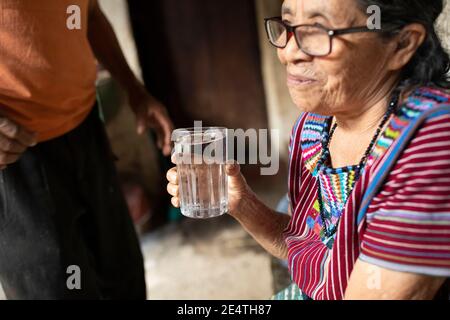 Une femme âgée boit un verre d'eau propre à San Juan la Laguna, Guatemala, Amérique centrale. Banque D'Images