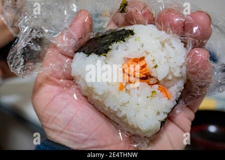 Gros plan d'une main tenant un riz au saumon Bal au Japon Banque D'Images
