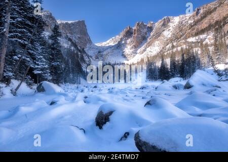 Des dérives de neige se forment au-dessus des rochers le long du rivage gelé du lac Dream, un lac populaire de haute altitude situé dans le parc national des montagnes Rocheuses Banque D'Images