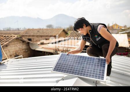 Un technicien de la société locale d'électricité à but non lucratif installe un nouveau système d'éclairage solaire dans une maison à Cantel, au Guatemala. Banque D'Images