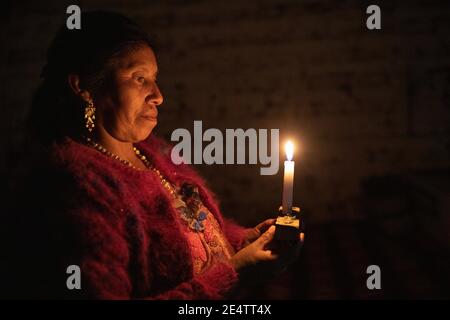 Une femme utilise une bougie comme source de lumière chez elle à Cantel, au Guatemala, en Amérique centrale. Banque D'Images