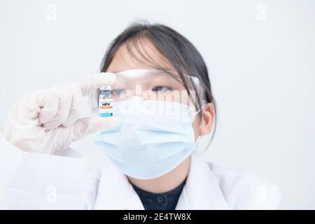 Peu de scientifiques ou de médecins détenant le vaccin contre le VPH sur fond blanc. Le vaccin protège contre la méningite et la coqueluche. Banque D'Images