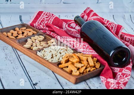 Assortiment d'en-cas et une bouteille de vin sur la table bleue. Craquelins, graines de tournesol, pistaches, amandes Banque D'Images