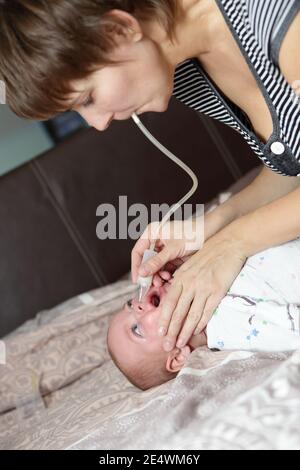 Mère utilisant un aspirateur nasal pour son fils Banque D'Images