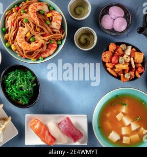 Cadre carré de cuisine japonaise avec espace de copie. Beaucoup de plats différents, pris d'en haut sur un fond bleu Banque D'Images