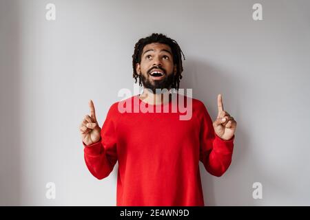 Surpris afro-américain homme regardant et pointant du doigt vers le haut isolé sur fond blanc Banque D'Images