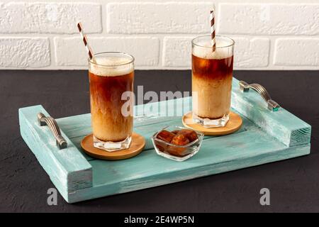 Un café glacé sur un plateau en bois avec de la crème versée dans celui-ci montrant la texture et l'aspect rafraîchissant de la boisson. Banque D'Images