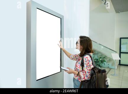 Femme avec téléphone utilise un bureau en libre-service avec écran tactile Banque D'Images
