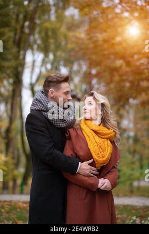 Rayon de soleil brillant sur le couple aimant homme et une femme embrassé de derrière sourire regardant les uns les autres dans le parc d'automne. Photo d'un jeune en plein air Banque D'Images