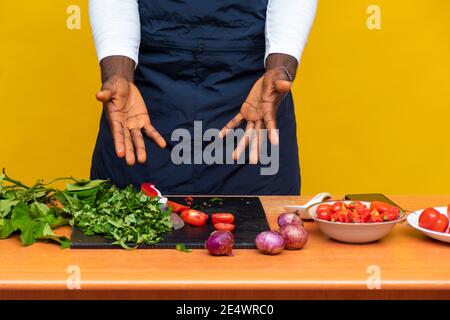 les mains d'un chef noir se contentaient de faire des gestes sur les ingrédients devant lui Banque D'Images