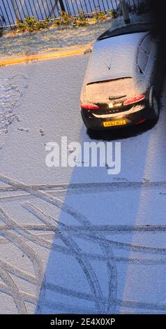 Vue en hauteur d'une berline enneigée il est dans un parking et des traces de pneus dans le neige Banque D'Images