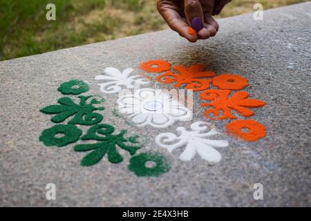Femme faisant des rangoli design tricolore safran blanc et Vert à l'occasion de la célébration de la veille de la république indienne Banque D'Images