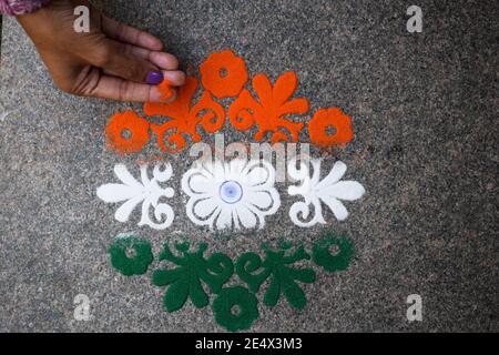 Femme faisant des rangoli design tricolore safran blanc et Vert à l'occasion de la célébration de la veille de la république indienne Banque D'Images