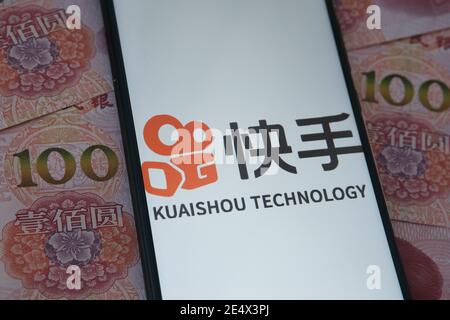 Stafford, Royaume-Uni - janvier 25 2021 : le logo de l'application Kuaishou est visible sur l'écran du smartphone et les billets de banque chinois en yuan sont flous en arrière-plan. Conc Banque D'Images