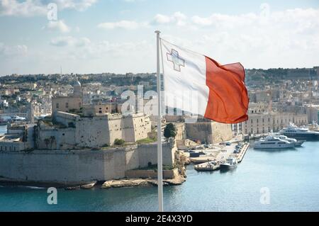 Le drapeau maltais vole depuis les jardins de la haute-Barrakka à la Valette et, en arrière-plan, le fort St. Angelo à Vittoriosa sur le Grand Port, Malte Banque D'Images