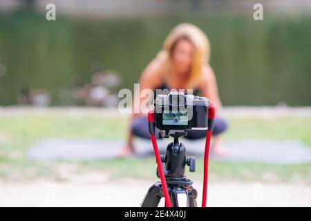 mise au point au premier plan d'un appareil photo numérique qui capture un effet de flou tout en faisant du yoga et des exercices sportifs dans le parc. Blogging et vlogging. Personnes Banque D'Images